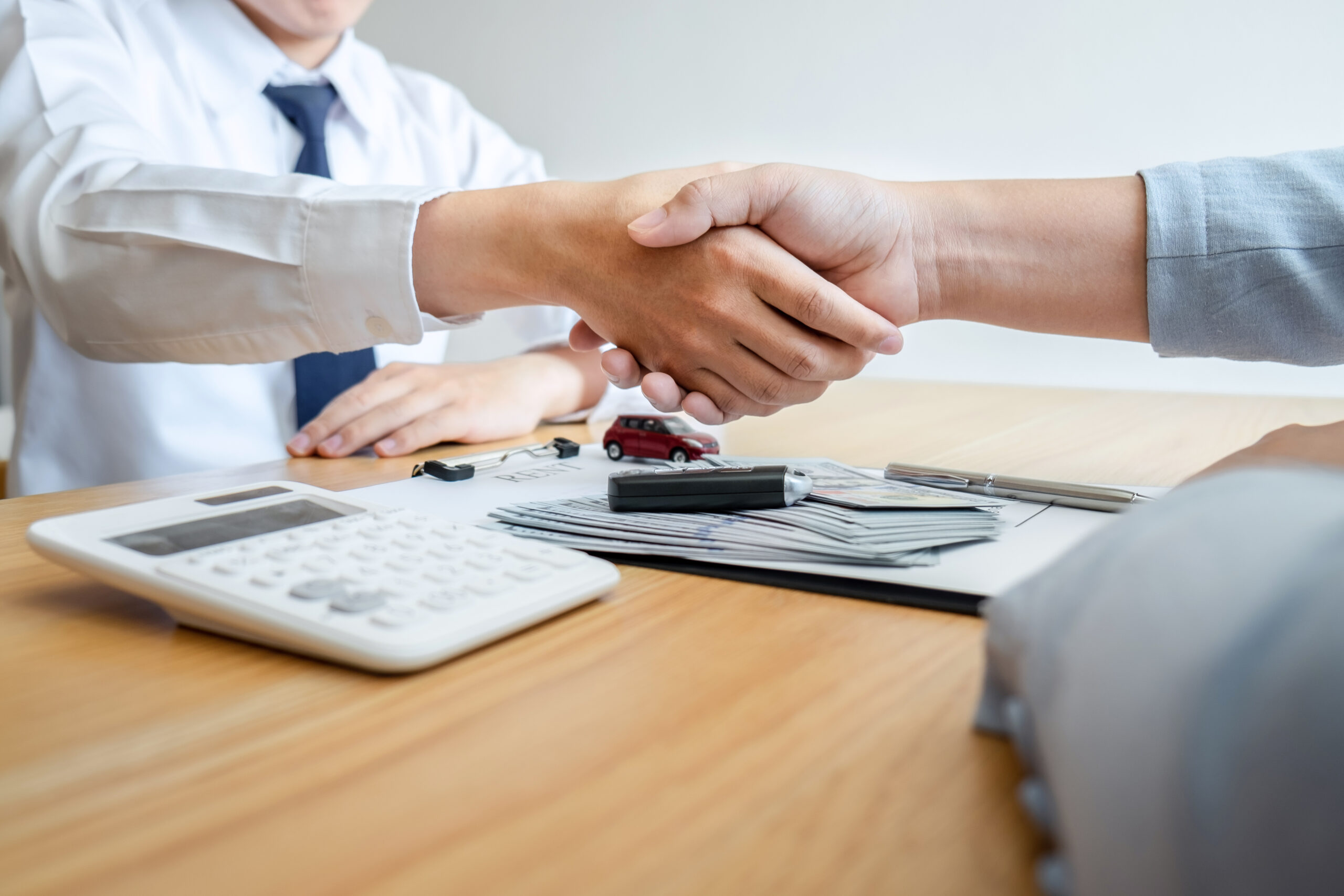 Car rental and Insurance concept, Young salesman shaking hands with customer after sign agreement contract with approved good deal for rent or purchase